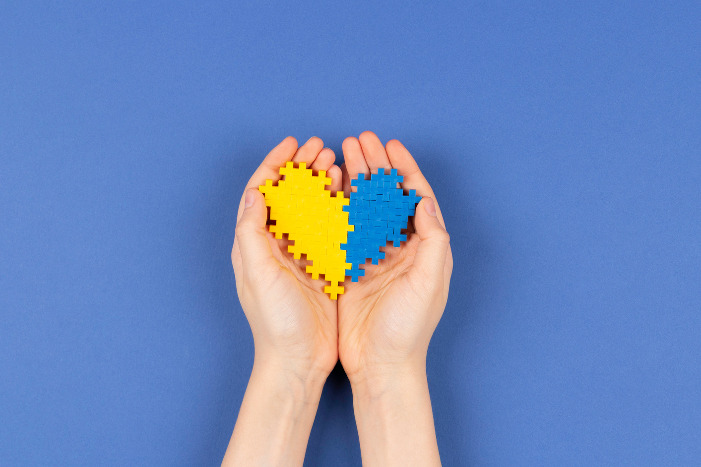 World down Syndrome Day Background. Hands Holding Blue and Yellow down Syndrome Awareness Day Heart on Navy Blue Background. Top View, Copy Space